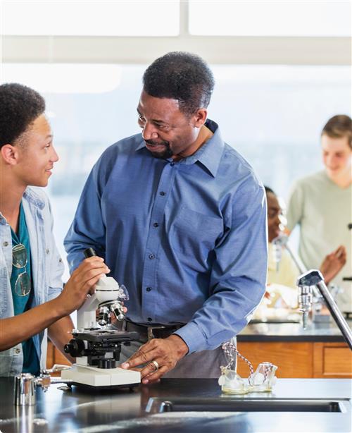 male teacher and students working with microscope