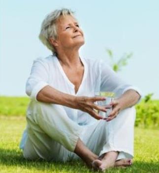 woman sitting on grass with glass of water in hand 