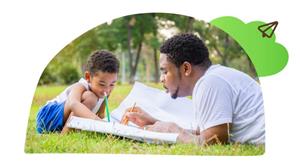 A man and child are sitting on the grass and appear to be drawing a picture.