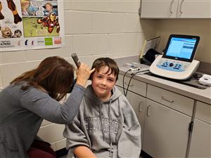 Audiologist checks student ears