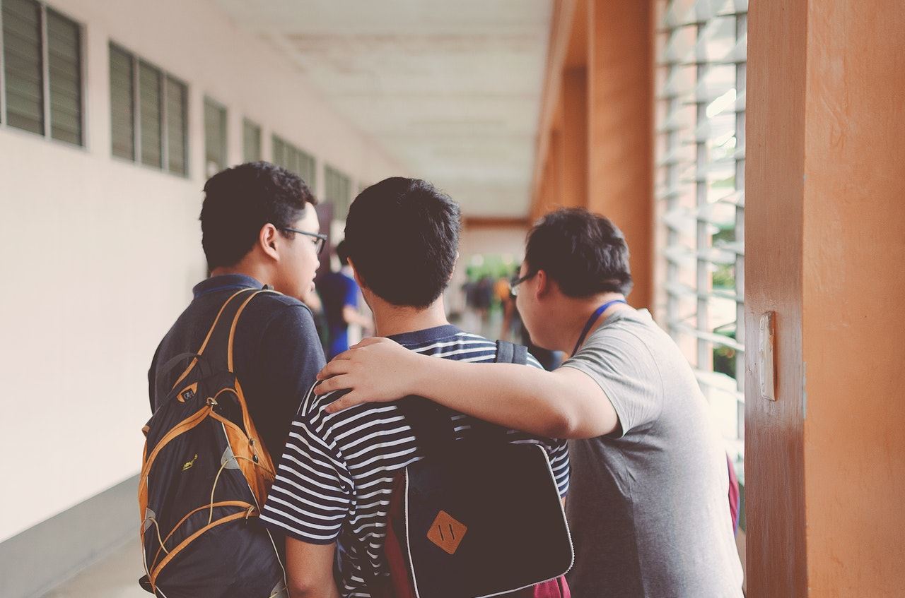 3 friends in hallway with backpacks