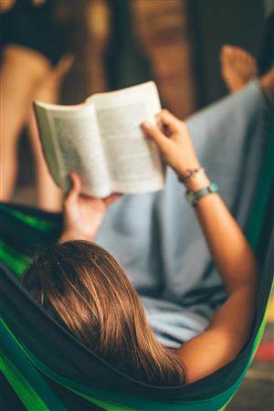 Child reading in hammock 