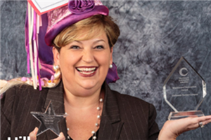 Ms. Hill holding up a blackboard award. 