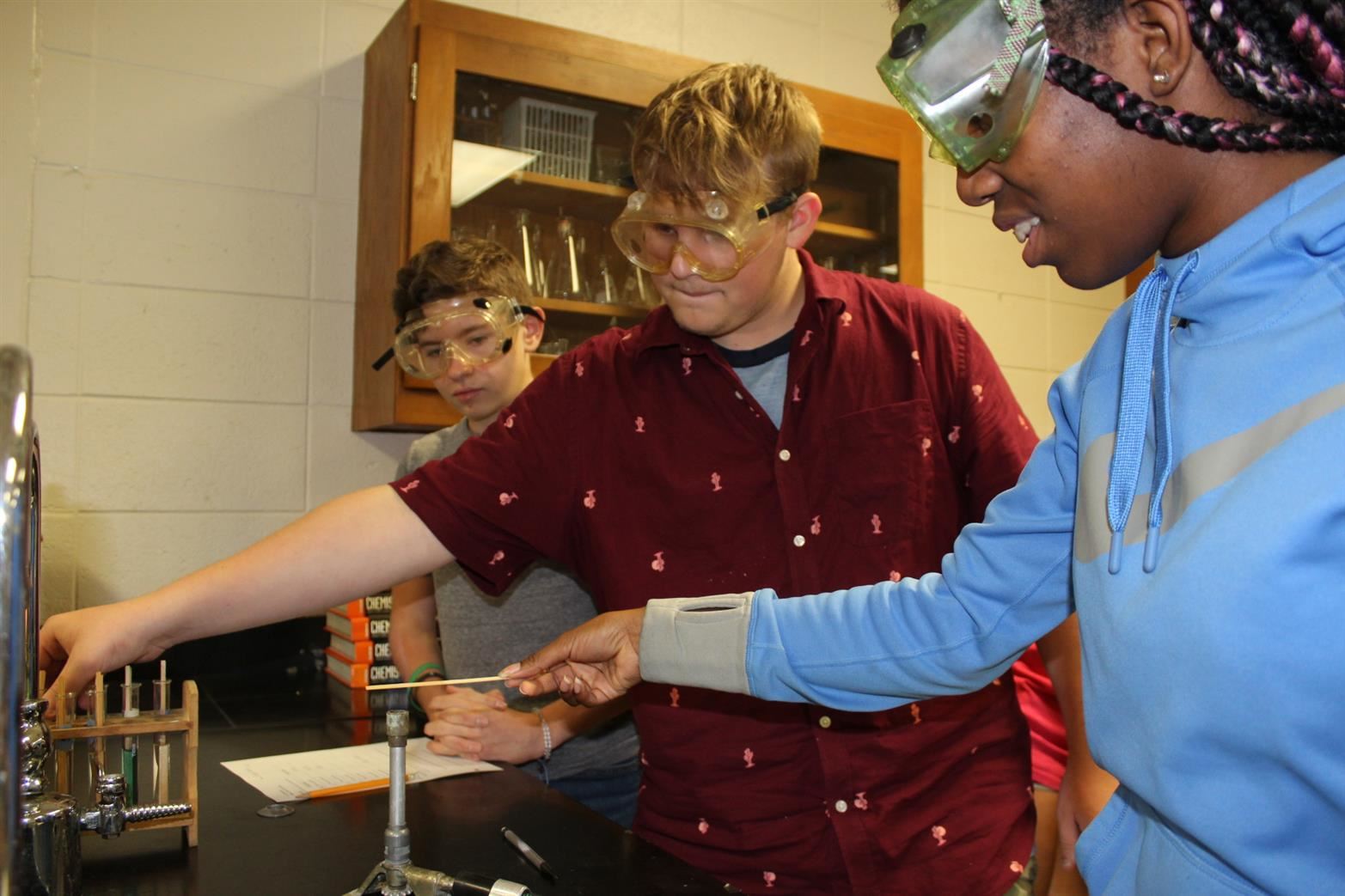 Students in chemistry class working with burner and chemicals